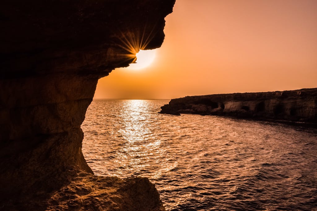 Breathtaking sunset over the ocean viewed from a Cyprus sea cave, creating a serene seascape.